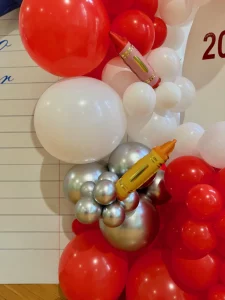 Kolorowa ścianka do zdjęć z motywem zeszytu szkolnego i balonami foliowymi