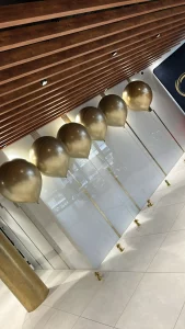 Duże złote balony kule z helem w nowoczesnym wnętrzu.