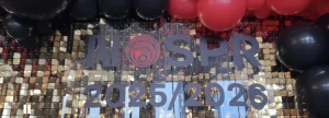 Złota ścianka do zdjęć z cekinów z logotypem na pleksi Nospr 2025/2026 i eleganckimi balonami