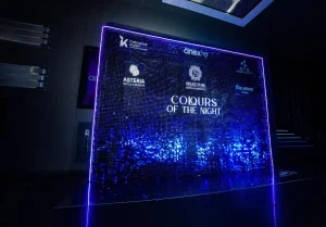 Ciemnoniebieska ścianka cekinowa z logotypami partnerów na przezroczystej pleksi na evencie Amex w Katowicach