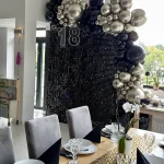 Czarna ścianka cekinowa z organiczną girlandą z czarnych i złotych balonów oraz świecącym napisem LED 18 na urodziny w restauracji Gilera w Świętochłowicach