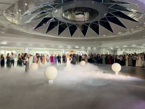 Para młoda tańcząca pierwszy taniec w ciężkim dymie, na którą spadają małe baloniki z wystrzałowych balonów