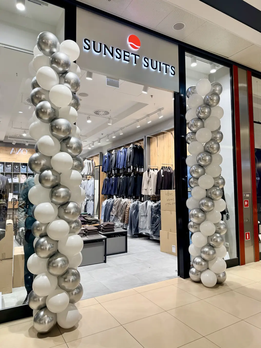 Trzymetrowe biało-srebrne kolumny balonowe przed salonem Sunset Suits w Galerii Echo Kielce.