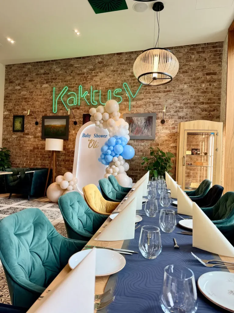 Zbliżenie na personalizowany napis Baby Shower Oli i asymetryczną, organiczną dekorację z ekologicznych balonów Gemar w kolorach białym, beżowym i błękitnym